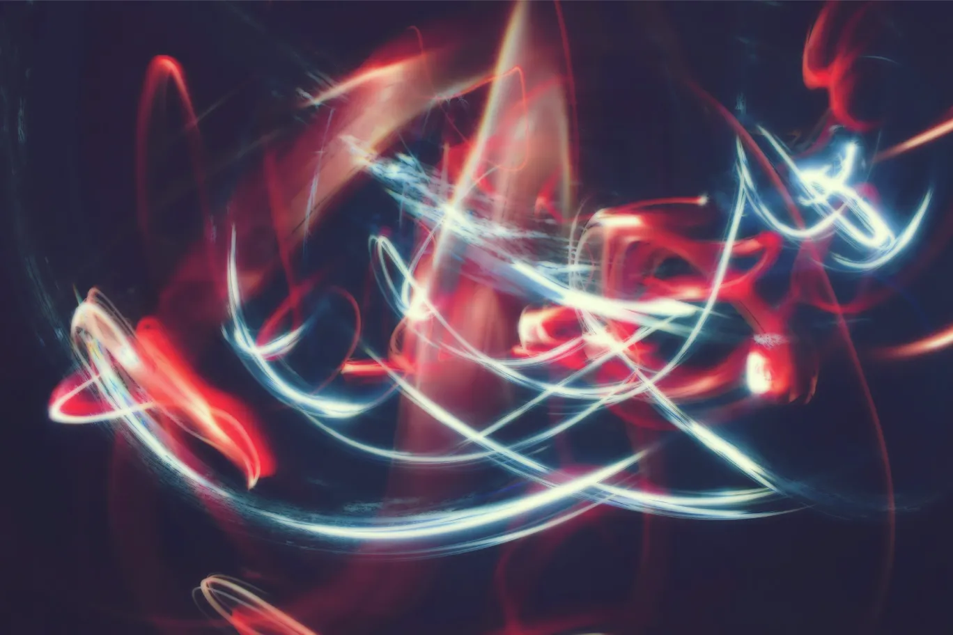 Light-painting long exposure of white and red streaks looping and crossing through darkness, suggesting tangled motion